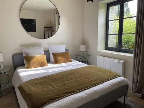 Modern bedroom at Clairseine cottage in Tournedos-sur-Seine with garden view, featuring gold accents and round mirror