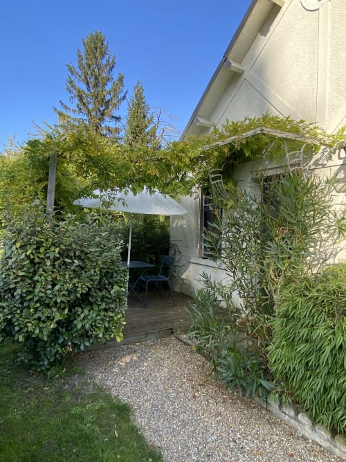 Private terrace garden at Clairseine cottage with shade pergola, lush greenery, and seating area in Tournedos-sur-Seine