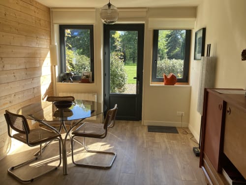 Bright dining room at The Nest cottage in Tournedos-sur-Seine with garden views through glass doors and windows, modern table
