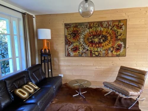 Modern cottage living room at Clairseine B&B with black leather sofa, sunflower artwork, and wooden walls