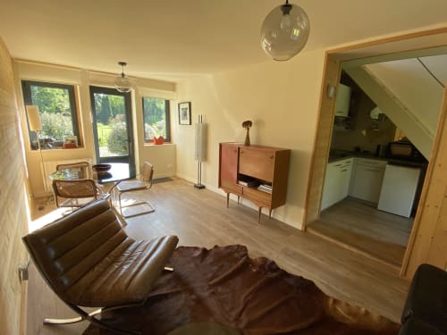 Modern cottage living room at Clairseine B&B with leather seating, wooden furniture, garden views, and open kitchen area.