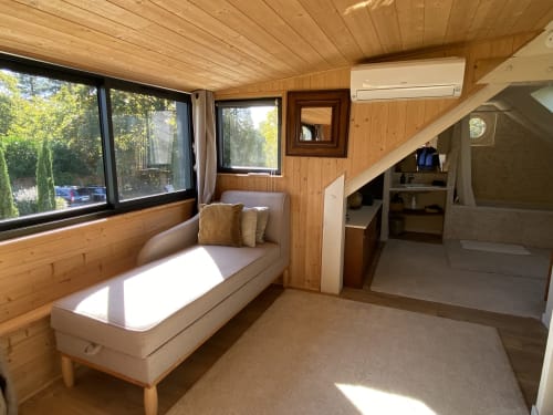 Bright wooden cottage interior with bench seating, river views, air conditioning, and modern amenities at Clairseine B&B