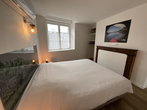 Bright bedroom at Locacharme cottage in Blois with white bedding, river view photo, window, and ambient lighting