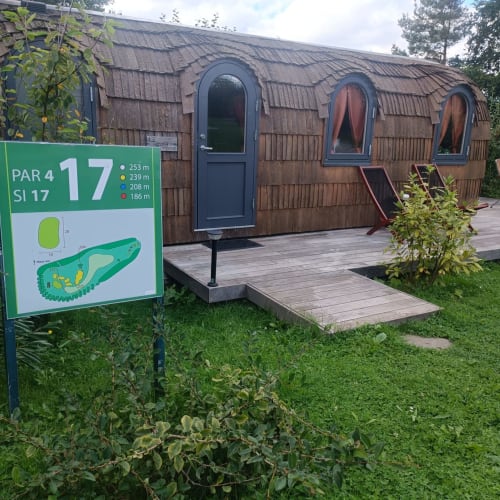 Holzhaus mit Bogenfenstern in Les Refuges Du Chalet, Jalhay, mit Golfplatz-Beschilderung im Garten