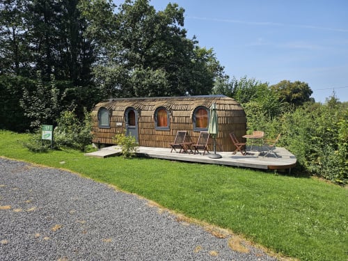 Holzhütte mit geschwungenem Dach in Les Refuges Du Chalet in Jalhay, Belgien, umgeben von grünen Gärten