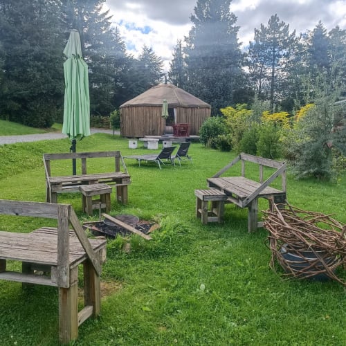 Yurt glamping with wooden seating areas and fire pit at Les Refuges Du Chalet in Jalhay, Belgium