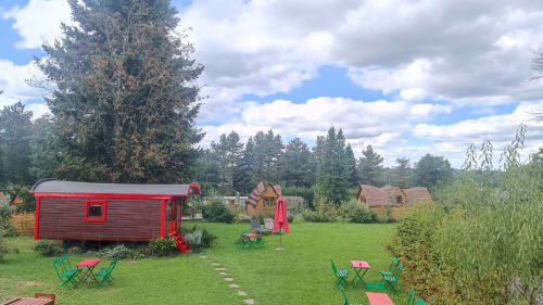 Red wooden glamping cabins with green seating areas at Les Refuges Du Chalet in Jalhay, Belgium