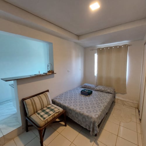 Quarto aconchegante na Pousada Serra Azul em Juquiá com cama, poltrona, kitchenette e vista para as montanhas