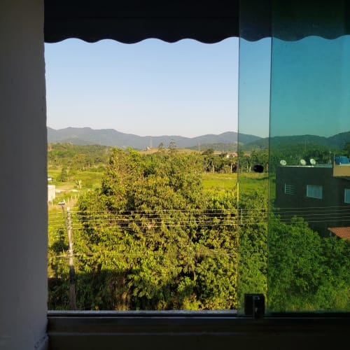Vista do vale montanhoso do quarto da Pousada Serra Azul em Juquiá, Brasil, com paisagem verdejante e colinas distantes
