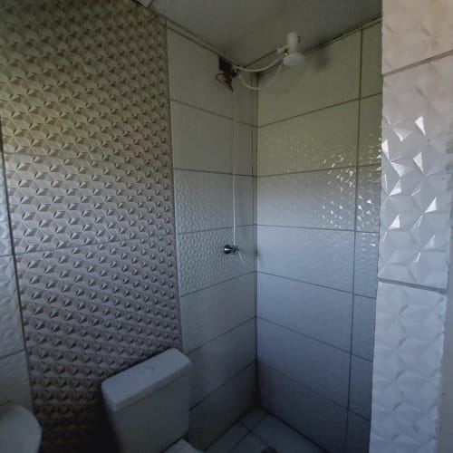 Banheiro moderno com azulejos texturizados na Pousada Serra Azul, Juquiá. Box de vidro e acessórios brancos.