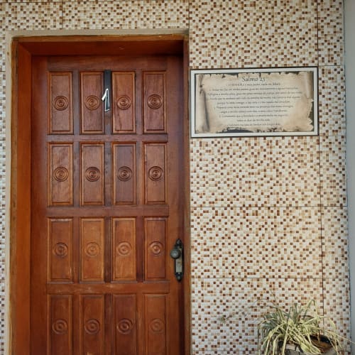 Porta de madeira com painéis circulares e placa do Salmo 23 na Pousada Serra Azul, Juquiá