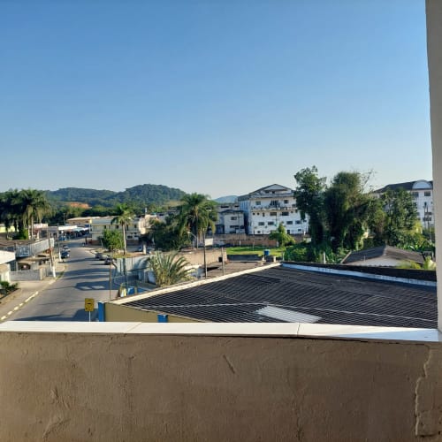 Vista da serra desde a varanda da Pousada Serra Azul em Juquiá, Brasil, com palmeiras e construções residenciais