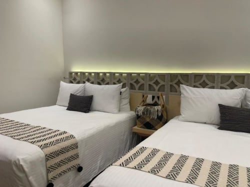 Dormitorio moderno en Casa Donceles con dos camas gemelas, sábanas blancas, mantas estampadas y cabecero geométrico