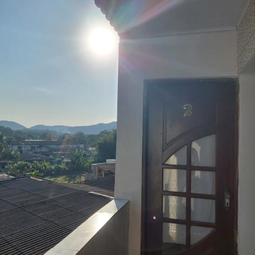 Porta de madeira escura numerada 2 na Pousada Serra Azul em Juquiá, com vista da cidade e montanhas ao fundo