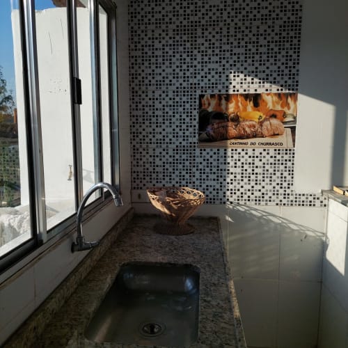 Pia da cozinha na Pousada Serra Azul com painel de azulejos em mosaico, cesto trançado e vista da cidade pela janela
