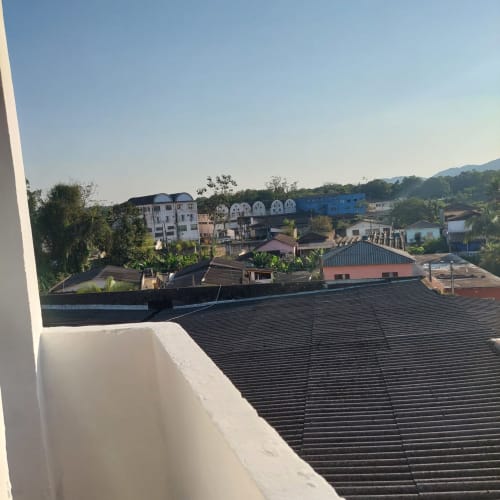 Vista da cidade desde a Pousada Serra Azul em Juquiá: telhados, edifícios residenciais e montanhas exuberantes