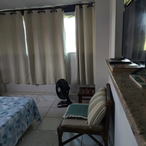 Quarto da Pousada Serra Azul em Juquiá com camas de solteiro, cortinas creme, ventilador e acesso à vista das montanhas