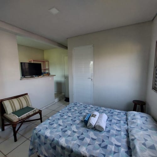 Quarto aconchegante na Pousada Serra Azul em Juquiá com cama de padrão azul, TV, cadeira listrada e vista para a serra