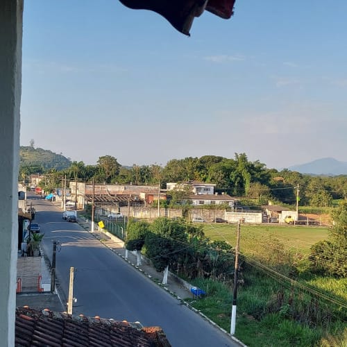 Vista da Serra Azul: pousada com pastagens verdes, estruturas locais e montanhas ao fundo em Juquiá