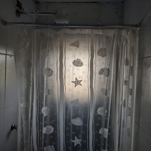 Cortina de chuveiro transparente com padrão de conchas e estrelas-do-mar na Pousada Serra Azul, Juquiá