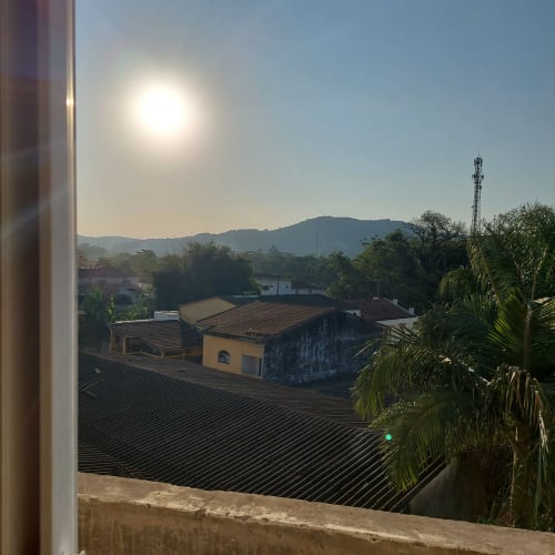 Vista da cidade da Pousada Serra Azul da varanda do apartamento com telhados de Juquiá, montanhas e torre de comunicação