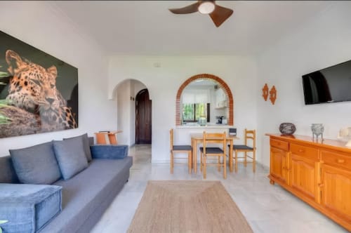 Sala de estar del apartamento SACORO en Marbella con sofá, muebles de madera, zona de comedor y arte de leopardo
