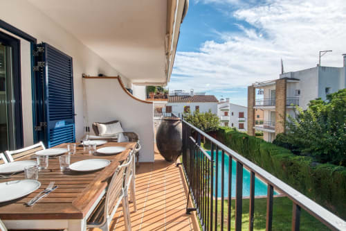 Terraza con mesa de comedor con vistas a la piscina y jardines mediterráneos del hotel Finques Garcia Enrich en Palafrugell