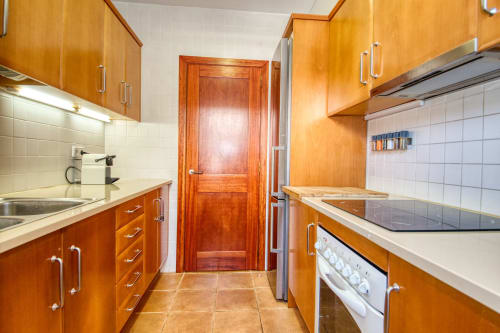 Cocina moderna con gabinetes de madera, backsplash de azulejos blancos y electrodomésticos de acero inoxidable en Finques Garcia Enrich