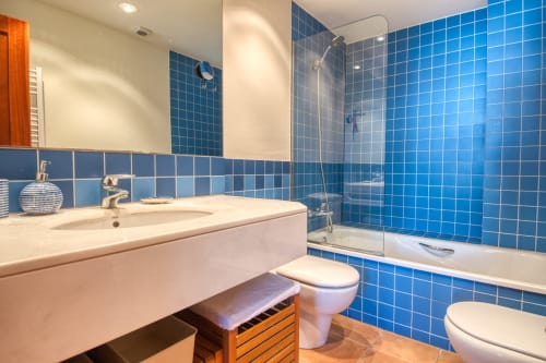 Baño moderno del hotel Finques Garcia Enrich en Palafrugell con azulejos azules, lavabo, inodoro y ducha