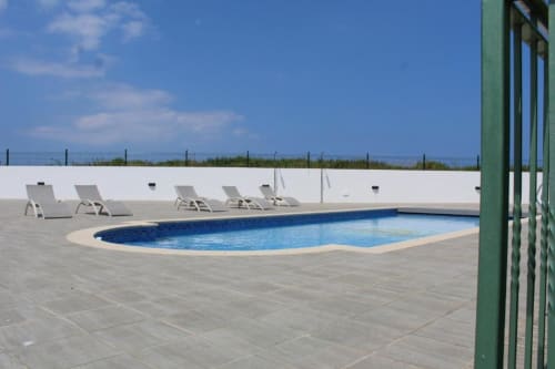 Piscina ovalada con tumbonas en Apartamentos Los Gemelos en Foz, Lugo, España