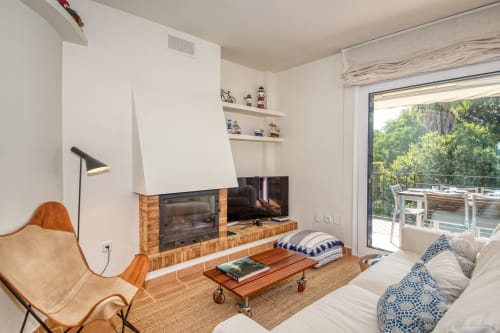 Modern apartment living room with fireplace, TV, comfortable seating, and garden view in Calella, Palafrugell