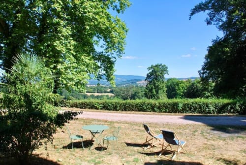 Riverside beach chairs at Château de Vaux Morvan B&B, Étang sur Arroux, with rolling vineyards and trees
