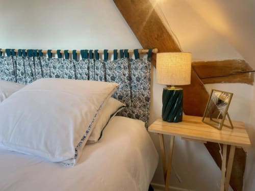 Cozy bedroom at Château de Vaux Morvan with white pillows, blue patterned headboard, wooden nightstand lamp, and rustic