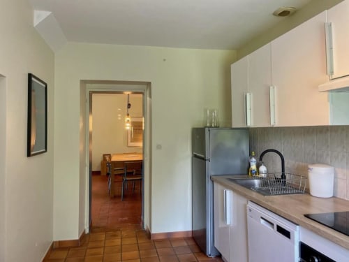 Kitchen with white cabinets, stainless steel appliances, and terra cotta tile flooring at Château de Vaux Morvan in Étang sur