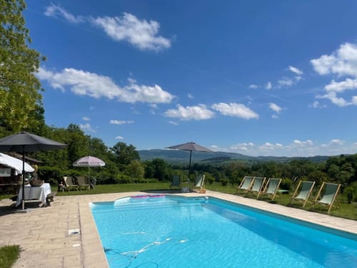 Swimming pool at Château de Vaux Morvan with mountain views, loungers, and umbrellas in Étang sur Arroux