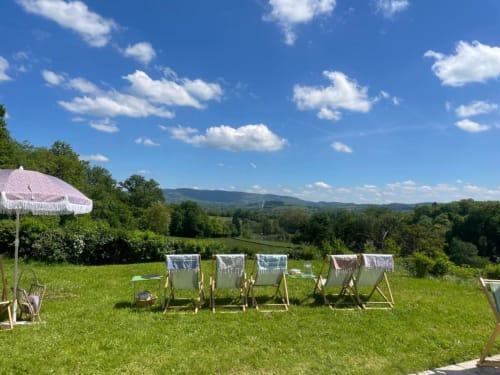 Transats alignés sur pelouse verte avec parapluie rose dominant la vallée du Morvan, Château de Vaux
