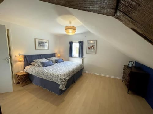 Spacious attic bedroom at Château de Vaux Morvan with queen bed, blue accents, wooden floors, and sloped ceiling