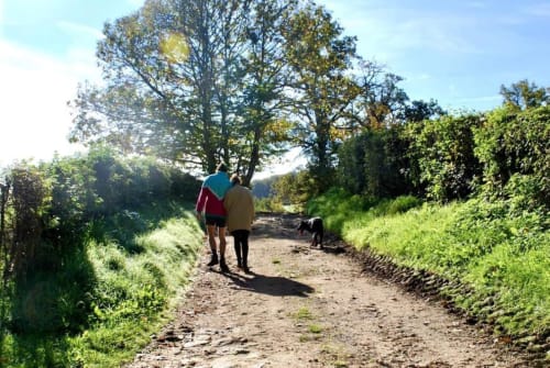 Two hikers walking on a scenic rural trail through green countryside near Château de Vaux Morvan in Étang sur Arroux, France