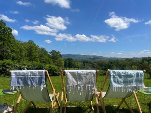 Linge mouillé séchant sur des transats dans une prairie verte avec montagnes et arbres au Château de Vaux Morvan