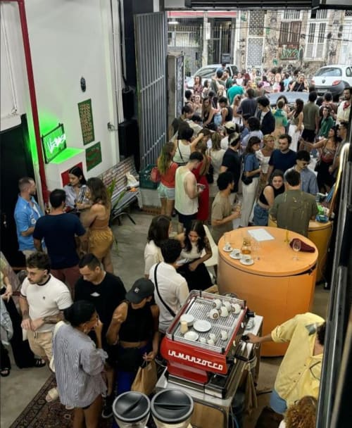 Crowded hostel event at Rio Vibes Hostel in Rio de Janeiro with guests socializing around coffee bar.