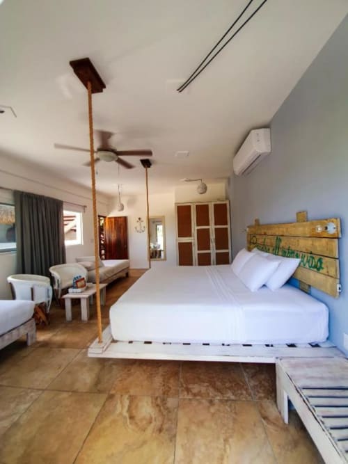 Moderna habitación en Hotel 40 Cañones en Mahahual con vista al océano, cama blanca, cabecera de madera y ventilador de techo