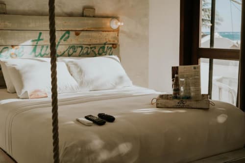 Habitación del Hotel 40 Cañones en Mahahual con cama de estructura de cuerda, almohadas blancas y vista al océano por la ventana