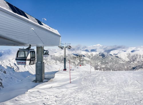 Mountain ski lift and cable car at Brides-les-Bains alpine resort with snowy peaks