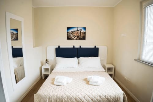 Camera moderna della Residence Balconi del Conero a Marcelli con letto matrimoniale, testata blu navy e quadri a tema costiero