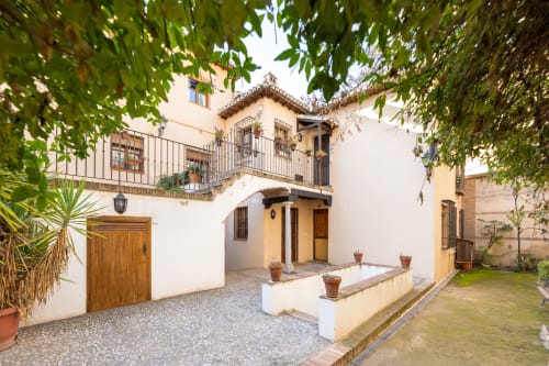 Encantador patio andaluz con escalinata, balcones floridos y detalles rústicos en un entorno tradicional y acogedor.