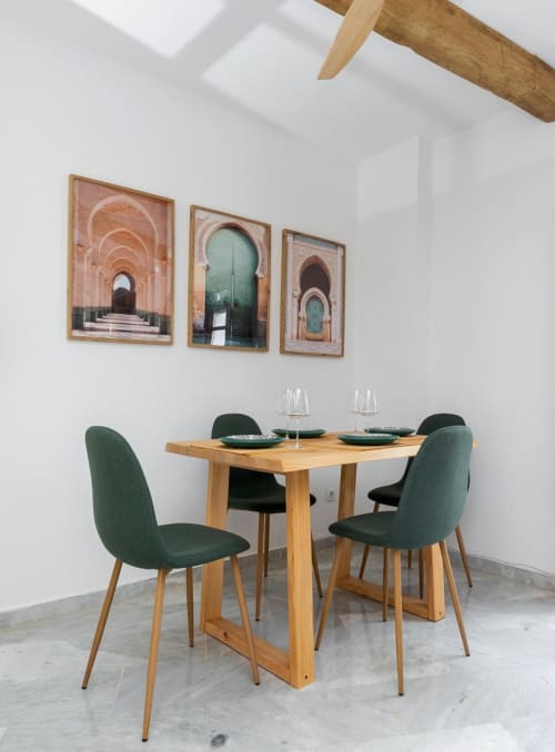 Comedor minimalista: mesa madera, sillas verdes y arte.

