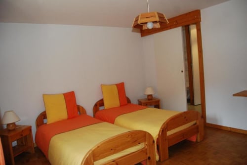 Lits jumeaux avec parure jaune et orange dans une chambre lumineuse aux Chambres d'hôtes le Grand Bienfaisy, Remiremont