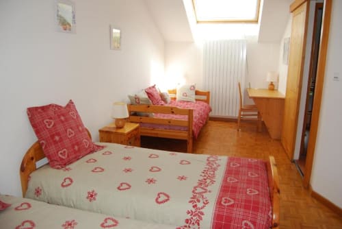 Chambre lumineuse sous les toits avec lits en bois, literie à motifs rouges, puits de lumière et parquet au Grand