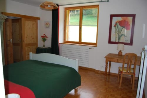 Chambre spacieuse avec literie verte à Chambres d'hôtes le Grand Bienfaisy à Remiremont, mobilier en bois et vue sur le jardin
