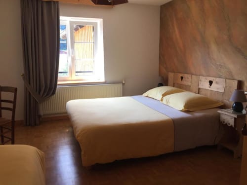 Chambre lumineuse avec lit en bois, oreillers jaunes et parquet aux Chambres d'hôtes le Grand Bienfaisy à Remiremont